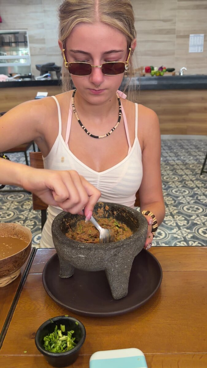 Making fresh guacamole in a stone molcajete during a Cozumel cooking class